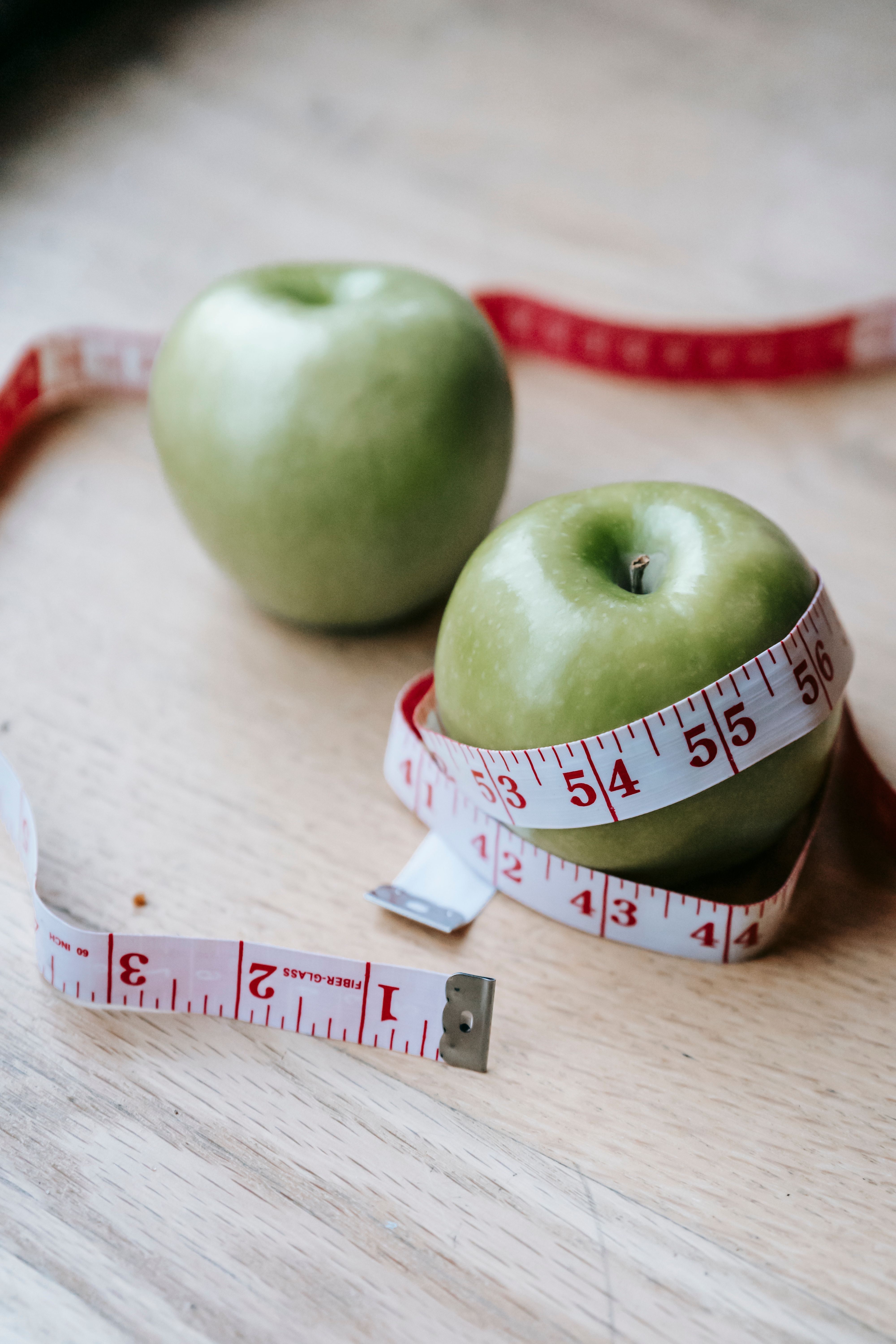 Green apples beside a tape measure on a table